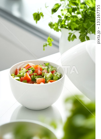 Fresh vegetable salad in a white bowl on a bright kitchen table 131167755