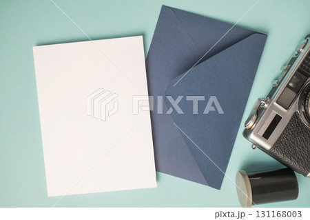 Empty white blank greeting or invitation card, envelope, vintage camera and film box on blue background. Empty white blank greeting or invitation card, envelope, vintage camera and film box on blue background. 131168003