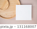 Empty white blank greeting or invitation card, wooden plate on beige background. 131168007