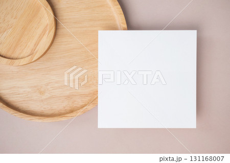 Empty white blank greeting or invitation card, wooden plate on beige background. 131168007