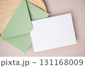 Empty white blank greeting or invitation card, envelope, wooden plate on beige background. 131168009