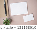 Empty white blank greeting or invitation card, name card, pen, note book, cactus on beige background. 131168010