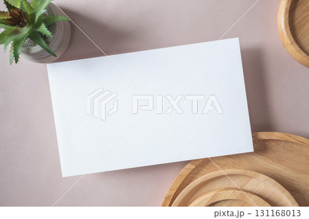 Empty white blank greeting or invitation card, cactus, wooden plate on beige background. Mock up presentation. Empty white blank greeting or invitation card, cactus, wooden plate on beige background. Mock up presentation. 131168013
