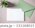 Empty white blank greeting or invitation card, green envelope, cactus on beige background. 131168015