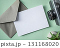 Empty white blank greeting or invitation card, envelope, vintage camera, cactus on green background. 131168020