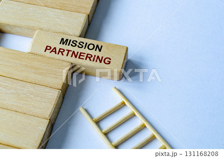 Mission Partnering text written on a wooden block placed on a ladder illustrating purpose driven objectives and direction. 131168208