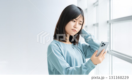スマートフォンを見て考える女性・ビジネスウーマン スマートフォンを見て考える女性・ビジネスウーマン 131168229