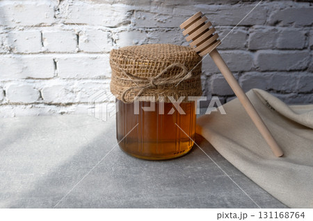 Honey jar with honeycomb and wood spoon stay on the stone table with napkin. Honey jar with honeycomb and wood spoon stay on the stone table with napkin. 131168764