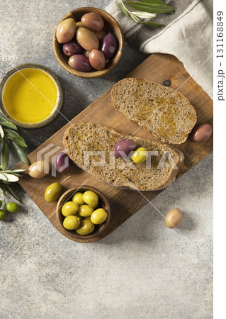 Mediterranean snack with mixed olives, olive oil, and rustic bread on wooden board. Mediterranean snack with mixed olives, olive oil, and rustic bread on wooden board. 131168849