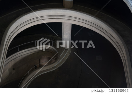 Spiral concrete staircase curves through circular tower creating dramatic architectural interior 131168965