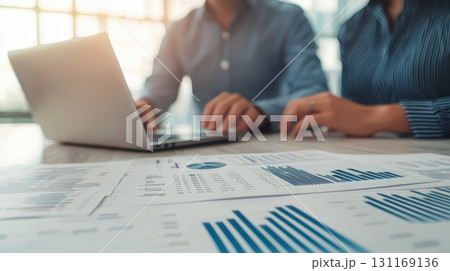 Couple reviewing property loan options with laptop and financial reports, analyzing data and discussing strategies for investment decisions 131169136