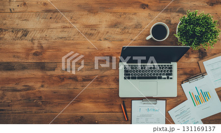 laptop on wooden desk with documents, coffee cup, and plant. workspace is organized and inviting, perfect for productivity and focus 131169137