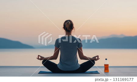 serene outdoor yoga session at sunset, featuring woman meditating by water. calm atmosphere enhances relaxation and mindfulness 131169177