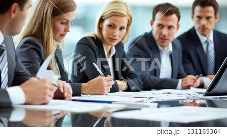 Business professionals engaged in meeting, reviewing documents and discussing strategies. atmosphere is focused and collaborative, highlighting teamwork and decision making 131169364