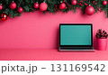 festive workspace featuring laptop, Christmas decorations, and pinecone plant. vibrant pink background adds cheerful touch to holiday season 131169542