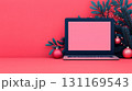 modern laptop on vibrant pink background, surrounded by festive decorations like ornaments and greenery, creating cheerful workspace atmosphere 131169543