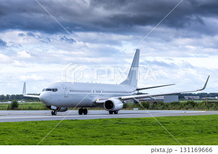 White passenger airplane taxiing at the taxiway at the airport in cloudy weather White passenger airplane taxiing at the taxiway at the airport in cloudy weather 131169666