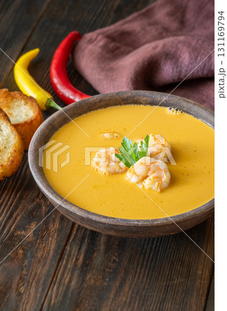 Rustic shrimp bisque with toasted baguette slices beside clay bowl 131169794