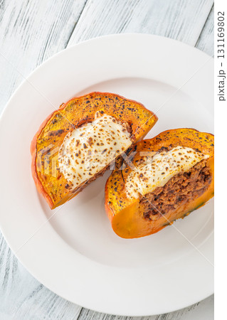 Portion of baked Hokkaido pumpkin with beef, tomato sauce, mozzarella cheese 131169802