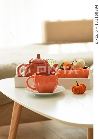 Autumnal living room decor with pumpkins, teapot, tea cup and cozy blankets. 131169894