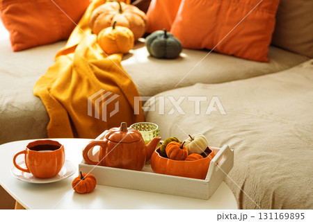 Autumnal living room decor with pumpkins, teapot, tea cup and cozy blankets. Autumnal living room decor with pumpkins, teapot, tea cup and cozy blankets. 131169895