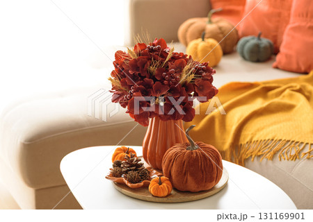 Thanksgiving living room decor with a coffee table, pumpkins and a floral arrangement. 131169901