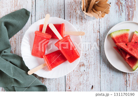 Watermelon popsicles on wooden sticks on a plate on a table top view 131170190
