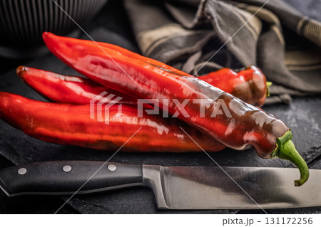 Corno di Toro Rosso pepper. Red paprika vegetable on black table. 131172256