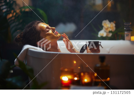 Woman in Gold Mask Applying Product During a Home Spa Bath 131172505