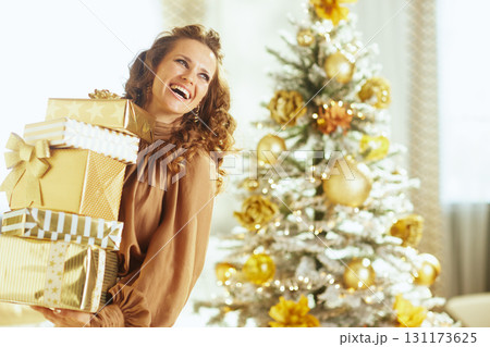 Smiling Woman with Gold Gifts and Festive Tree Smiling Woman with Gold Gifts and Festive Tree 131173625