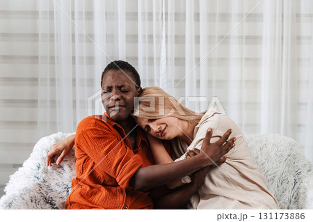 Two Young Women Embracing and Showing Support on a Sofa Two Young Women Embracing and Showing Support on a Sofa 131173886