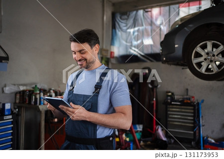 Car mechanic using a digital tablet in a repair shop 131173953