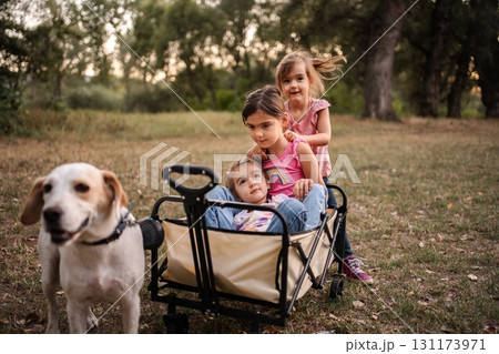 Dog pulling wagon with three little girls in a park Dog pulling wagon with three little girls in a park 131173971