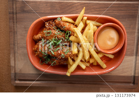 Crispy chicken wings served with golden fries and dipping sauce on wooden table Crispy chicken wings served with golden fries and dipping sauce on wooden table 131173974