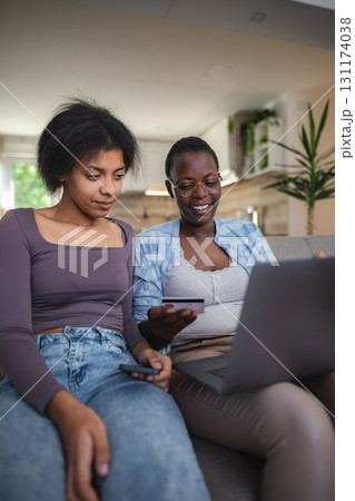 Two young women shopping online using laptop and credit card at home Two young women shopping online using laptop and credit card at home 131174038