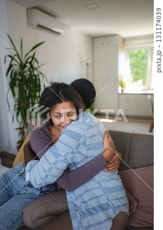 Two Teenager Sisters are Hugging on the Sofa at Home 131174039