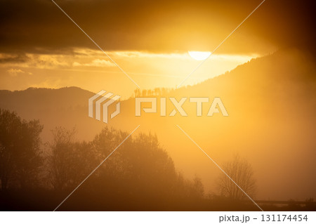 Golden hour bathes mountains and trees in a warm glow, creating a serene and peaceful atmosphere. Golden hour bathes mountains and trees in a warm glow, creating a serene and peaceful atmosphere. 131174454