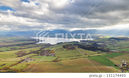 The Liptovska Mara dam in northern Slovakia, Europe. Scenic view of a large lake surrounded by green fields and distant mountains under a cloudy sky. 131174493