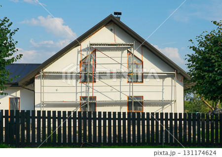 Modern white house under renovation with scaffolding and black wooden fence in residential area Modern white house under renovation with scaffolding and black wooden fence in residential area 131174624