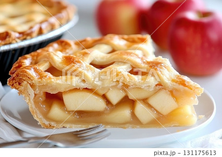 Delicious homemade apple pie slice with lattice crust and fresh apples on a white plate 131175613