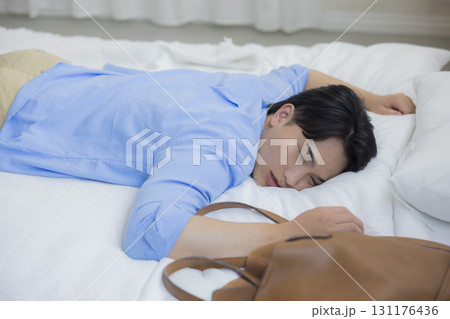 ベッドに倒れ込む男性 131176436