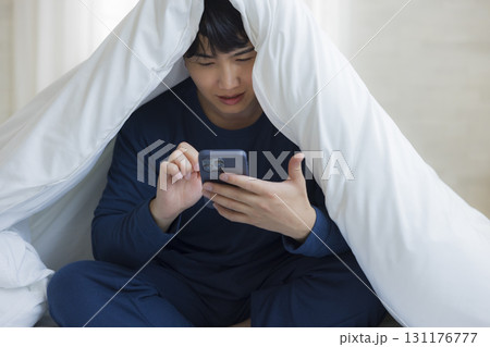 布団に潜る男性 131176777