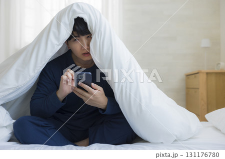布団に潜る男性 131176780