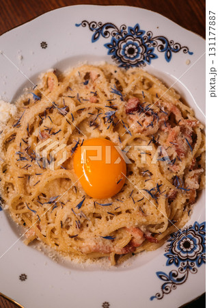 Served pasta. Traditional italian dish. Appetizing noodles with egg yolk on plate. Tasty carbonara recipe with grated cheese seasoning. Served pasta. Traditional italian dish. Appetizing noodles with egg yolk on plate. Tasty carbonara recipe with grated cheese seasoning. 131177887