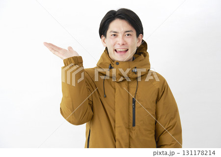 ダウンジャケットを着た男性　左側を手のひらで指す　白背景 131178214