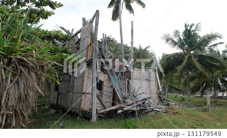 Stormy winds shake palm trees with bamboo hut debris scattered after powerful coastal typhoon Stormy winds shake palm trees with bamboo hut debris scattered after powerful coastal typhoon 131179549