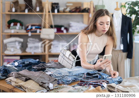 Selective young woman scanning QR-code on pantaloons in clothing store 131180906