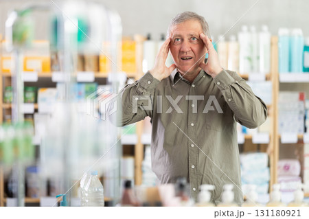 Senior man visits pharmacy and suffers from headache 131180921