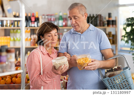 Senior couple is holding two packages of flakes in hands, choosing food for garnish side dish 131180997