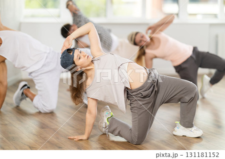 Girl and her students perform hip hop dance on one bent leg, movement in horizontal plane near floor Girl and her students perform hip hop dance on one bent leg, movement in horizontal plane near floor 131181152